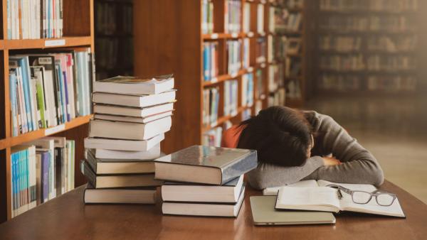 lawyer sleeping at a table covered with books in a library